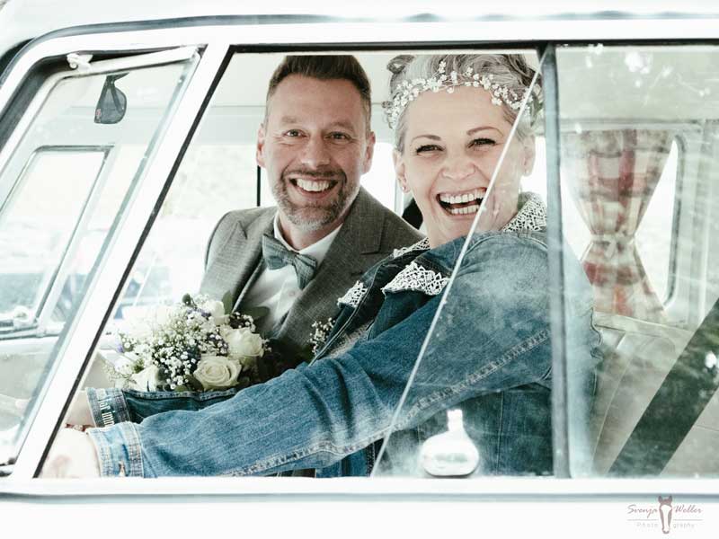 Brautpaar herzlich lachend in altem VW Bus