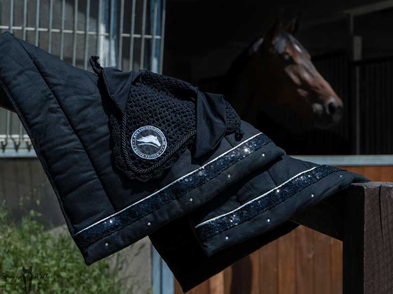 Schwarze bandagierunterlagen mit Paliette und Fliegenmütze von Equiworld official Pferd im Hintergrund
