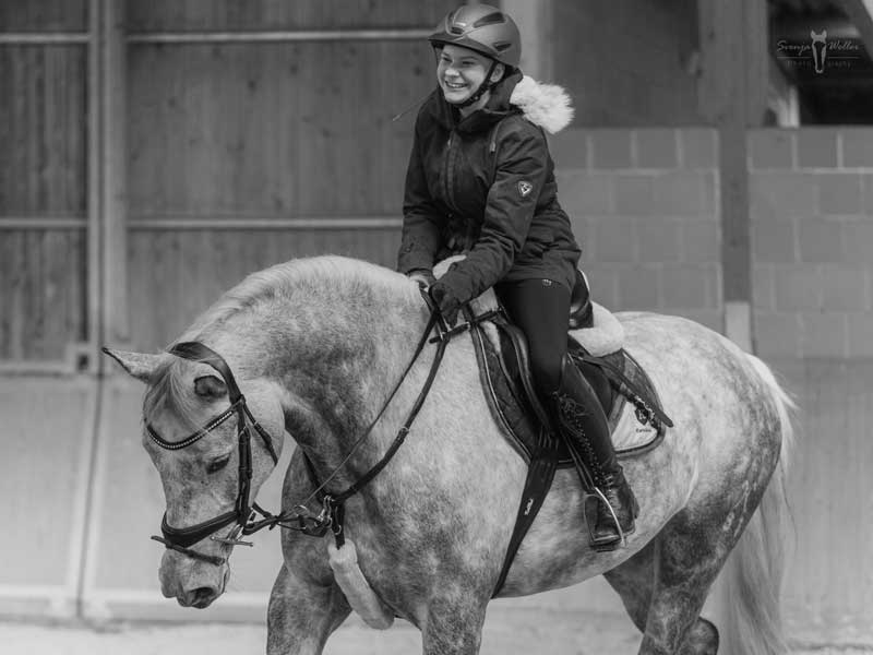Schwarz weiß Portrait, Schimmel mit Reiterin fröhlich im Training